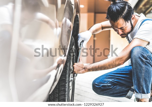 Fixing car engine in automobile repair garage.\
Handsome mechanics in uniform are repairing car while working in\
auto service
