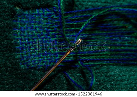 Fixing a hole in a green sofa by darning it.