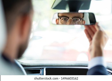 Fixing Mirror. Young Businessman Wearing Glasses Fixing Rear View Mirror Before Driving His Car