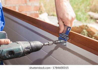 Fixing And Replacement Concept. Cropped View Of Professional Worker Using Electric Screwdriver And Install New Garage Door System In House Under Construction