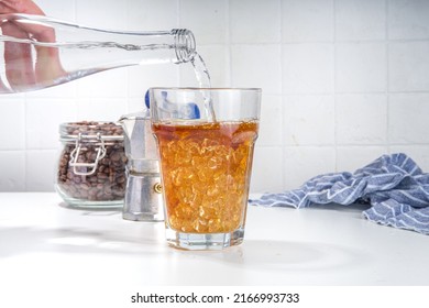 Fizzy coffee drink. Coffee espresso with carbonated mineral water and crushed ice, with coffee maker, milk roasted coffee beans on white background copy space