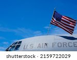 The flag of America is hanging over a military airplane part of the US Air Force. Army industry in this difficult times of war.