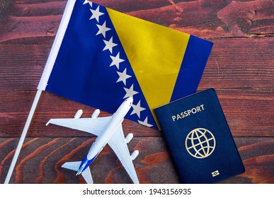 Flag Of Bosnia And Herzegovina With Passport And Toy Airplane On Wooden Background. Flight Travel Concept.