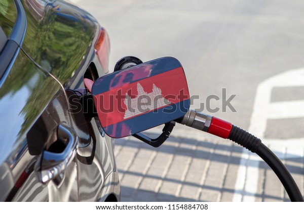 Flag of Cambodia on the car\'s fuel\
tank filler flap. Fueling car with petrol pump at a gas station.\
Petrol station. Gasoline and oil products. Close\
up.