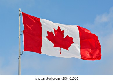 Flag of Canada flying against a blue sky.    