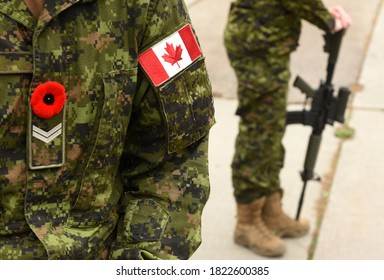 Flag Of Canada On The Military Uniform And Soldier With Weapon On The Background. Canadian Soldiers. Canadian Army. Remembrance Day.Poppy Day. 