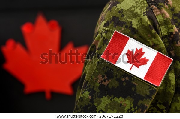 Flag of Canada on the military\
uniform and red Maple leaf on the background. Canadian soldiers.\
Army of Canada. Remembrance Day. Poppy day. Canada\
Day.