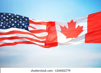 Flag Of Canada And The USA Against The Background Of The Blue Sky