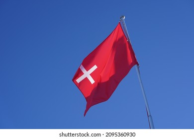 Flag of Canton Schwyz blowing in the wind at mountain village Stoos on a sunny winter day. Photo taken December 20th, 2021, Stoos, Switzerland.
