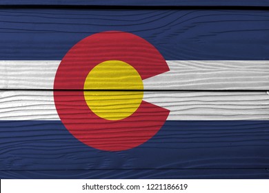 Flag of Colorado on wooden wall background. Grunge Colorado flag texture, The states of America, blue white and blue. On top of these stripes sits a circular red "C" with a golden disk.