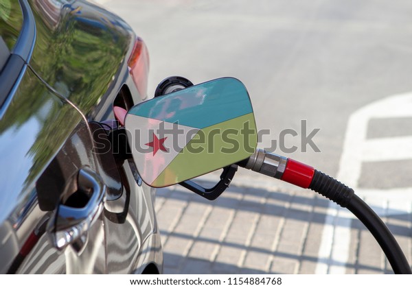Flag of Djibouti on the car\'s fuel\
tank filler flap. Fueling car with petrol pump at a gas station.\
Petrol station. Gasoline and oil products. Close\
up.