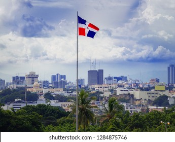 flag of the Dominican Republic on the background of the panorama of Santa Domingo and thunderclouds