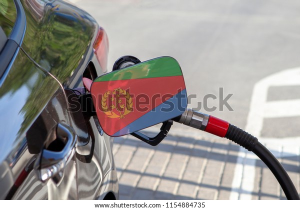 Flag of Eritrea on the car\'s fuel\
tank filler flap. Fueling car with petrol pump at a gas station.\
Petrol station. Gasoline and oil products. Close\
up.