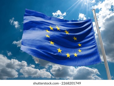 Flag of the European Union waving in the wind on flagpole against background of the sunrise, banner, close-up