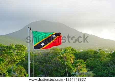 Flag of the Federation of St Kitts and Nevis floating in front of the Nevis volcano