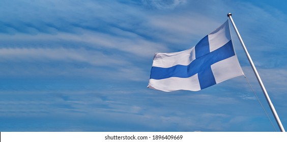 Flag of Finland, also called the Blue Cross flag, the national flag of the Republic of Finland against a pastel blue sky, panorama with an empty space, mock up