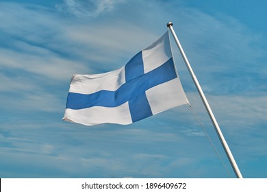 Flag of Finland located in front of the blue sky. The flag flutters in the wind. Windy, sunny and clear weather. Finland, the Finnish flag. Blue Cross on the flag.