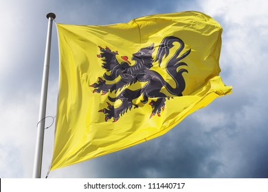 Flag of Flanders (part of Belgium) waving against a dramatic cloudy sky