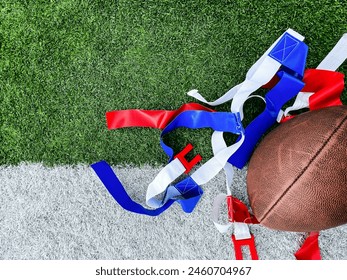 Flag Football Equipment on Green Turf. White belts with red and blue flags used for playing flag football. A football lays to the side. Set against the white and green turf of a football field. - Powered by Shutterstock