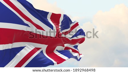 Flag of Great Britain being waved in the breeze against a sunset sky.