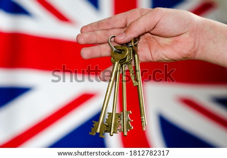 Flag Of Great Britain. Hand holding a bunch of antique keys on the background of the English flag. Soft focus.