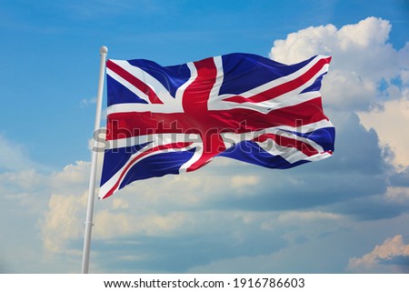 Flag of Great Britan being waved in the breeze against a sunset sky.