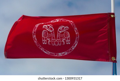 The flag of the Haida people of Haida Gwaii. White print on a bright red field, depicting the two moieties, the Eagle and the Raven. Snapping in the breeze. - Shutterstock ID 1300931317