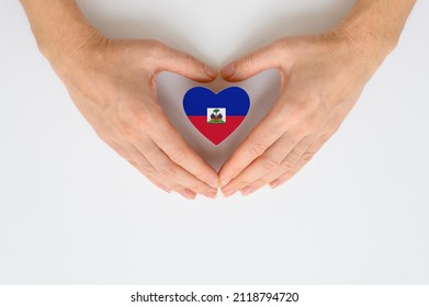 Flag of Haiti in the shape of a heart in female hands. The concept of providing humanitarian assistance to Haiti. - Shutterstock ID 2118794720