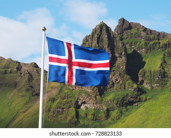 Flag of Iceland against the background of green mountains and blue sky