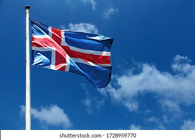 Flag of Iceland on a high flagpole. Waving Icelandic Flag Against a Blue Sky with Clouds. National Flag of Iceland. Image for Icelandic Republic Day, National Day