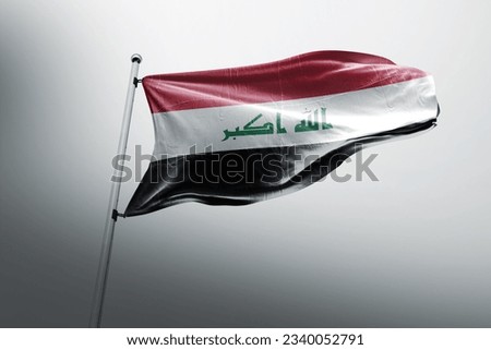 The flag of Iraq ncludes the three equal horizontal red, white, and black stripes of the Arab Liberation flag, with the phrase God is the greatest in Arabic written in Kufic script in the center. [[stock_photo]] © 