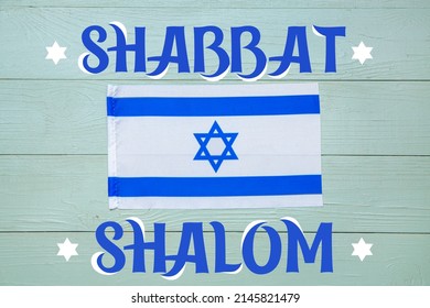 Flag of Israel and text SHABBAT SHALOM on color wooden background