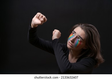 Flag LGBT Lizbian Woman With Rainbow Tears On Her Cheek Defends Herself With Her Hands In Front Of Her On A Black Background. The Girl Is Scared For Their Sexual Orientation. Discrimination Concept