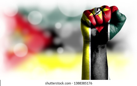 Flag Of Mozambique Painted On Male Fist, Strength,power,concept Of Conflict. On A Blurred Background With A Good Place For Your Text.