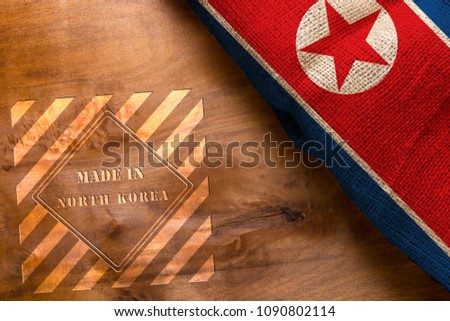 Flag of North Korea made from rough fabric on a wooden background and stamp made in North Korea