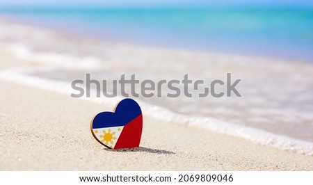 Flag of the Philippines in the shape of a heart on a sandy beach. The concept of the best vacation in Philippine resorts