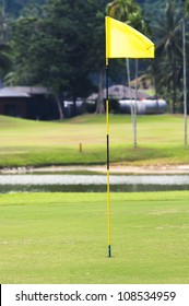 Flag Pole In Hole Of A Golf Course.