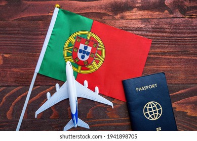 Flag of Portugal with passport and toy airplane on wooden background. Flight travel concept.