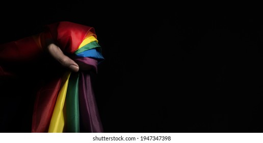 Flag Of Pride. LGBTQ Flag And Hand. Lesbian Gay Bi Sexsual Transgender Queer Or Homosexsual Pride Rainbow Flag. Black Background. Represent Hand Symbol Of Freedom Equality.