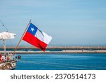 Flag of the Republic of Chile, waving on the stern of a training ship anchored in the port