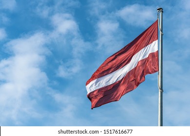 Flag of the Republic of Latvia. Flag of Latvia against the blue sky. Copy space.