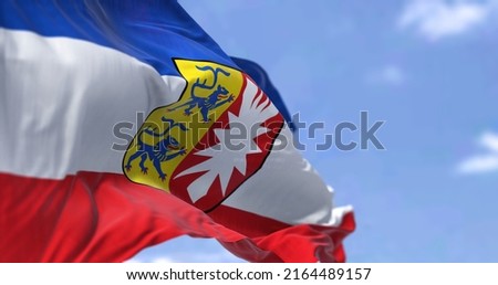 The flag of Schleswig-Holstein waving in the wind on a clear day. Schleswig-Holstein is a German state (Land) situated in northern Germany