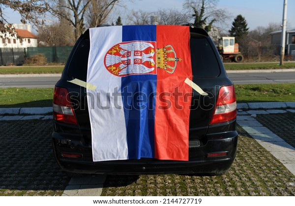 Flag of\
Serbia. Car is covered by a Serbian\
flag.