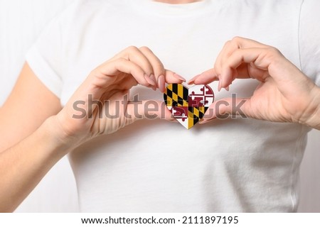 Flag of the state of Maryland in the shape of a heart in the hands of a girl. Love Maryland. The concept of patriotism