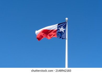 Flag Of Texas Waving In The Wind With Blue Sky In The Background. 
Texas Is A State In The South Central Region Of The United States.
