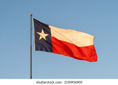 Flag Of Texas Waving In The Wind With Blue Sky In Background. Texas Is A State In The South Central Region Of The United States.