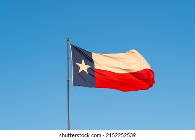 Flag Of Texas Waving In The Wind With Blue Sky In Background. Texas Is A State In The South Central Region Of The United States.