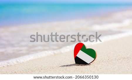 Flag of UAE in the shape of a heart on a sandy beach. The concept of the best vacation in United Arab Emirates resorts