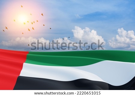 Flag of United Arab Emirates on background of blue sky with flying birds. UAE celebration. National day, Flag day, Commemoration day, Martyrs day.