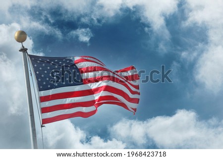 Flag of the United States of America over blue sky white clouds background